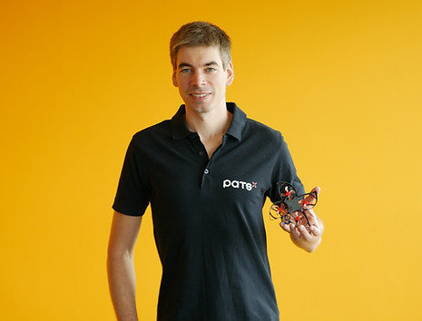 Man wearing a PATS shirt holding a small drone