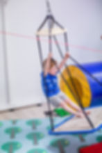Boy swinging on a sensory platform swing during an individual occupational therapy session