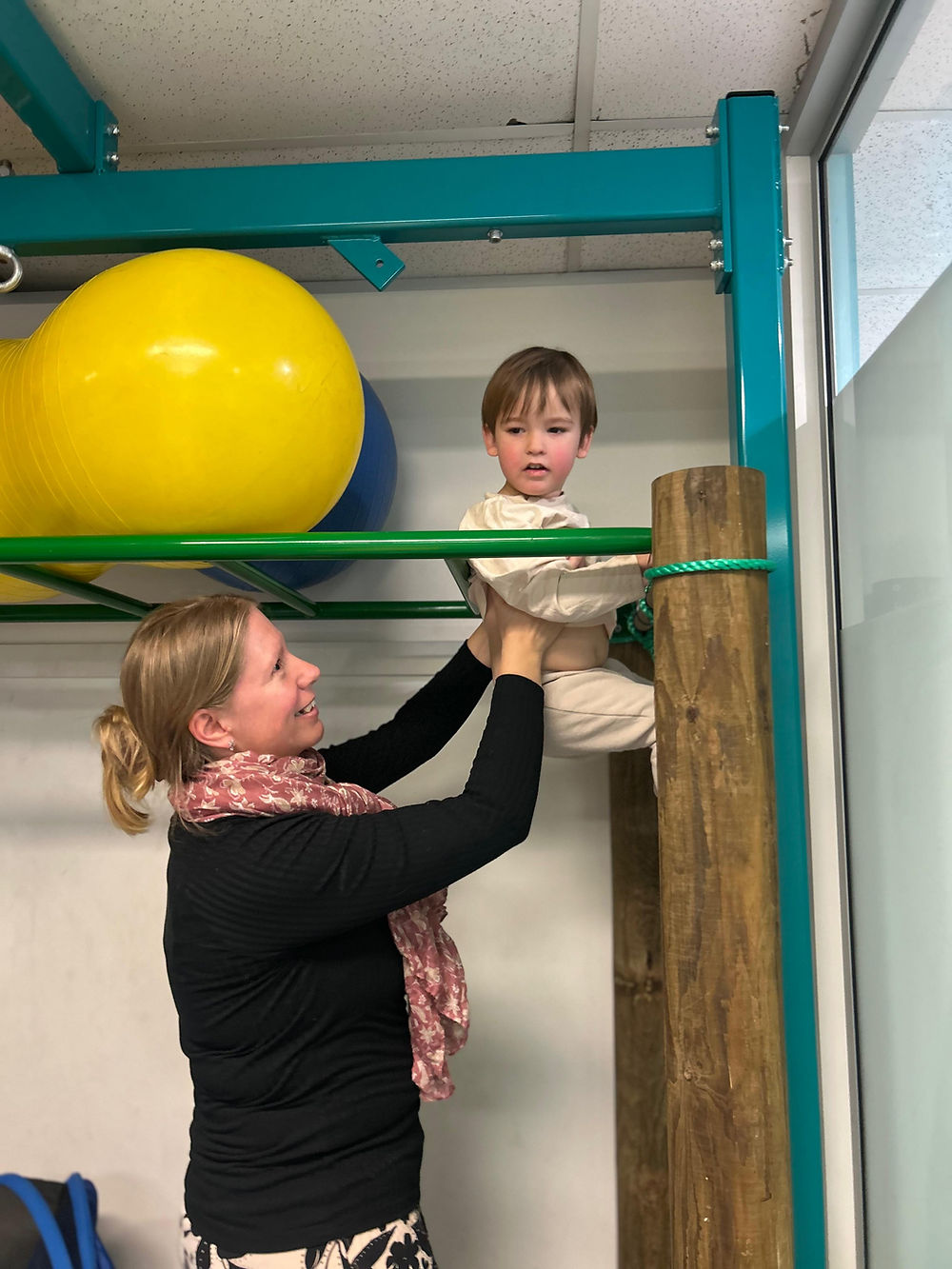 Occupational therapist helping a child on monkey bars