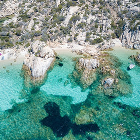 Vista dall'alto di tre piccole calette una di fianco all'altra con acqua chiarissima color smeraldo
