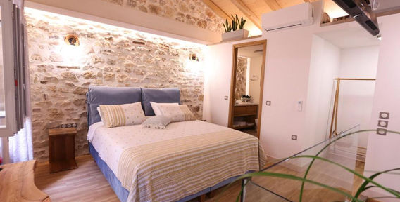 Stone wall bedroom and timber ceiling at Viaggio Historical Suite Corfu