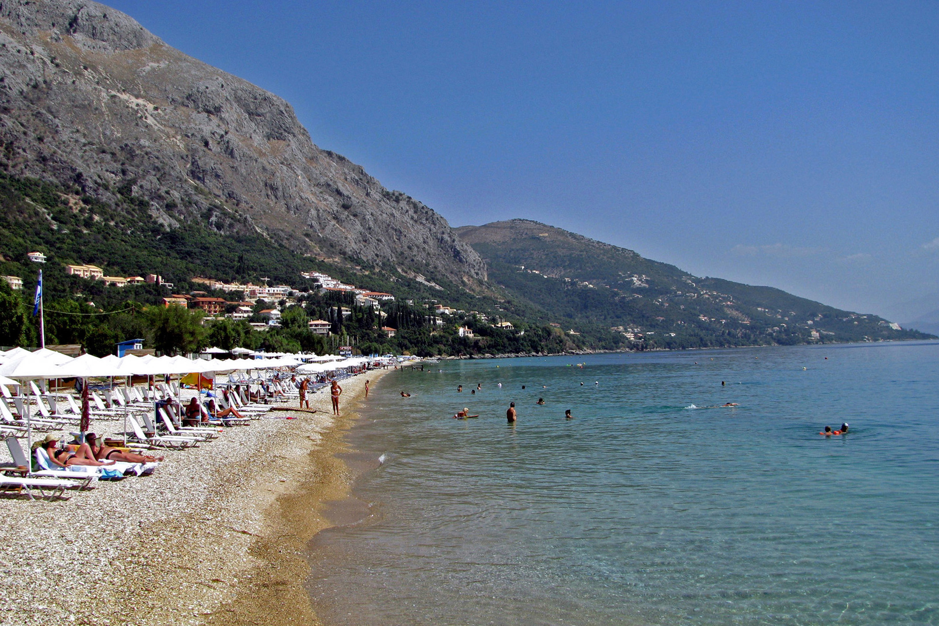 Parts of the beach are organised with seasonal sunbeds and parasols, while other stretches remain more open.