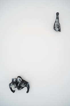 Pair of two vampire Bats in black and white cast glass in the lower left corner and a single Bat with the same materials in the upper right corner with an open mouth on a white background