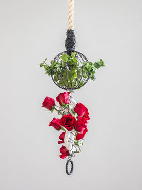 Sculpture hanging from the ceiling by a rope containing herbs and roses 