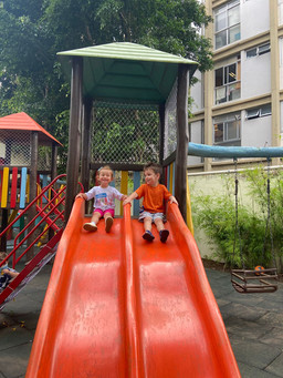 duas crianças brincando no escorregador do parque