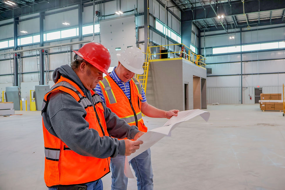 Two construction workers looking at a set of plans in a warehouse