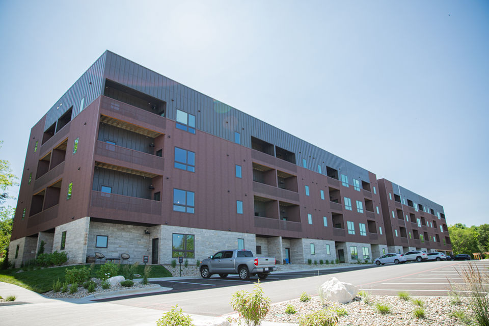 Exterior photo of the dark brown, four-story apartment complex.