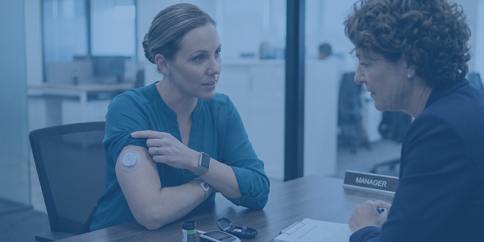 An employee shows a glucose monitor on her arm to a manager during a performance meeting.