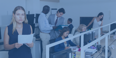 Puzzled woman standing with papers in hands in open plan office