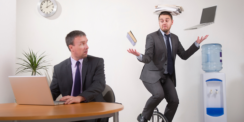 Two businessmen in an office; one sits at a desk with a laptop, looking on in shock as the other rides a unicycle while balancing a stack of papers on his head and juggling a book and another laptop.