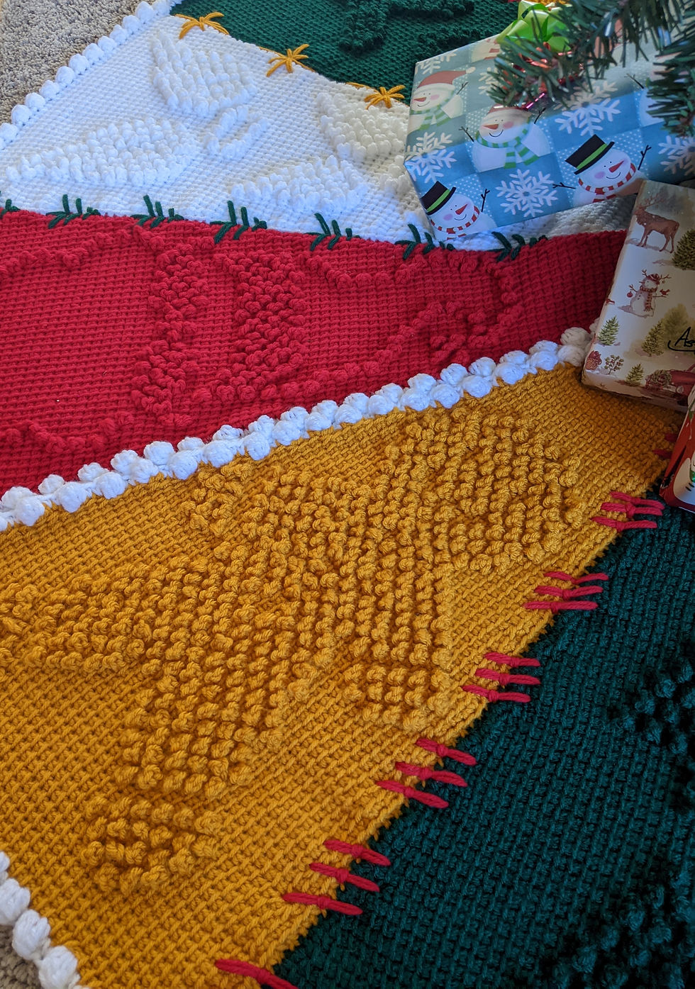 Thumbnail: Tunisian Crochet Christmas Tree Skirt Pattern with 12 panels with individual holiday motifs