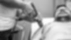 A black and white photo of a healthcare professional applying a handheld shockwave therapy device to a male patient's shoulder during a clinical treatment session.
