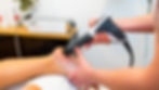 A close-up of a person’s foot with gel applied while a therapist uses a shockwave therapy devicA close-up of a person’s foot with gel applied while a therapist usesne spur treatment.e for bone spur treatment. a shockwave therapy device for bo