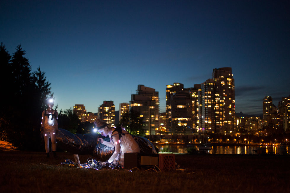 People setting up lights at night, city skyline