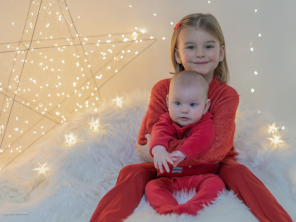 Gemeinsam im Weihnachtslicht - Geschwisterportrait mit Weihnachtsstern und Lichterkette
