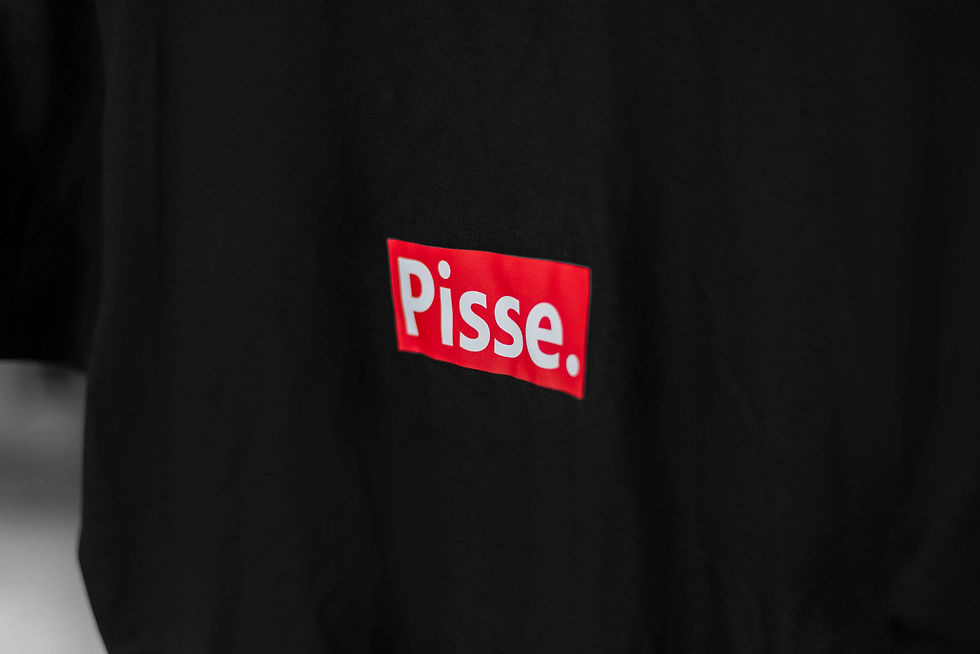 Miniaturbild: Nahaufnahme eines schwarzen "Pisse." Shirt mit einem roten "Pisse." Aufdruck.