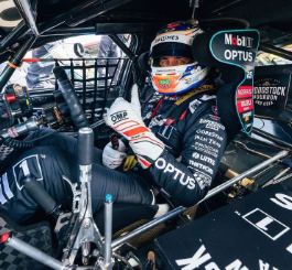 Racing Driver sitting in car with white helmet giving thumbs up
