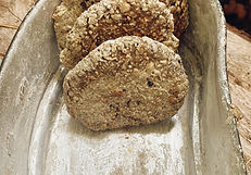 Selbstgebackenes Survival-Brot aus handgemahlenem Mehl – rustikale Fladenbrote in einer Feldschale, frisch zubereitet über dem Feuer während eines Outdoor-Survivaltrainings