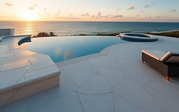 marble white paver pool deck overlooking the gulf in Florida with a sunset and blue skies_
