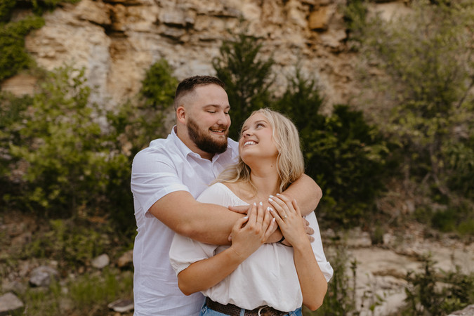 Happy engaged couple smiling during outdoor St. Louis engagement session with natural scenery.