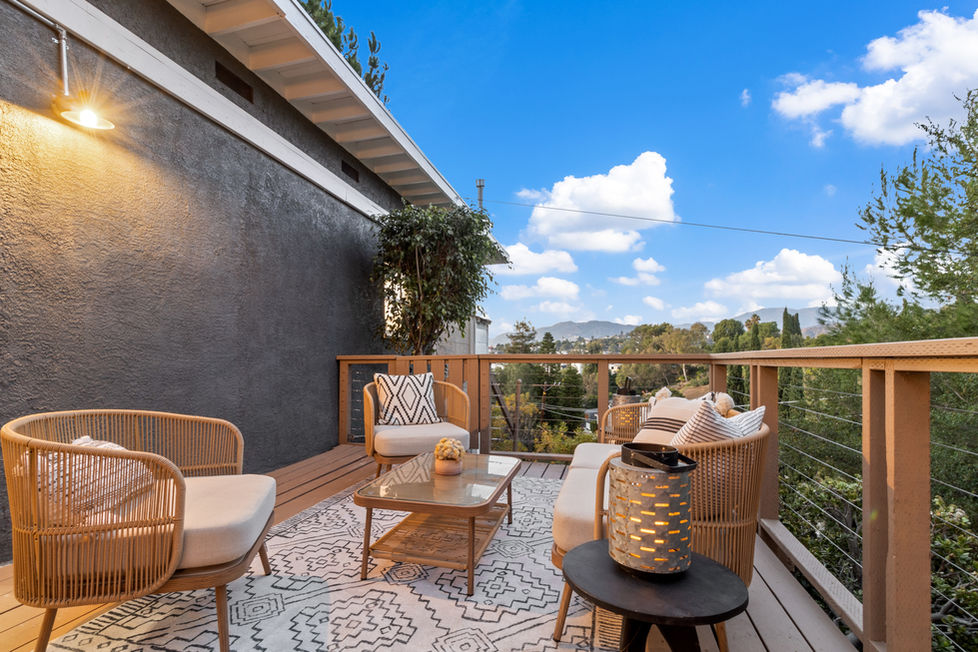 a balcony with chairs and a table with a lantern on it overlooking the neighborhood