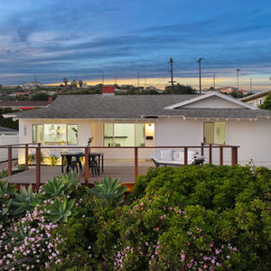 a white house with a composite deck and flowers in front of it