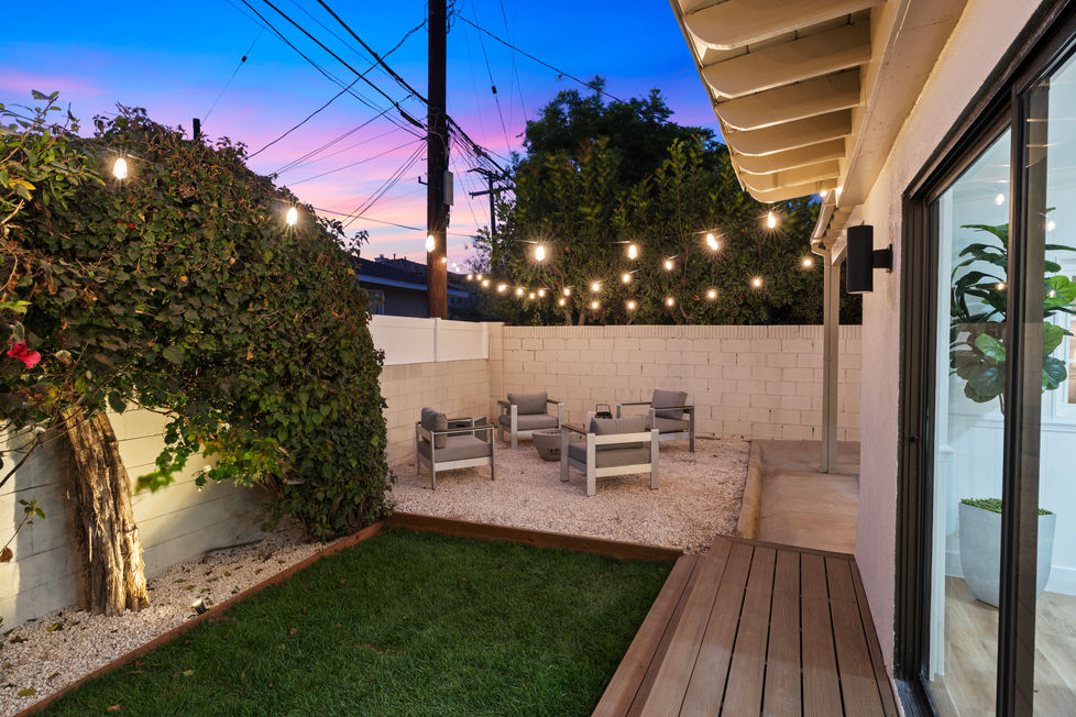a patio with chairs and string lights hanging from the ceiling