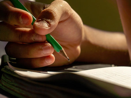 A person holding a pencil above paper