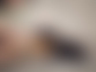 Small brown puppy mouthing a person's forefinger on a background of sand.