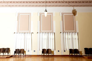 Inside of Memorial Hall with restored seats, restored light pendant, and intricately laid ceiling and restored hardwood flooring.