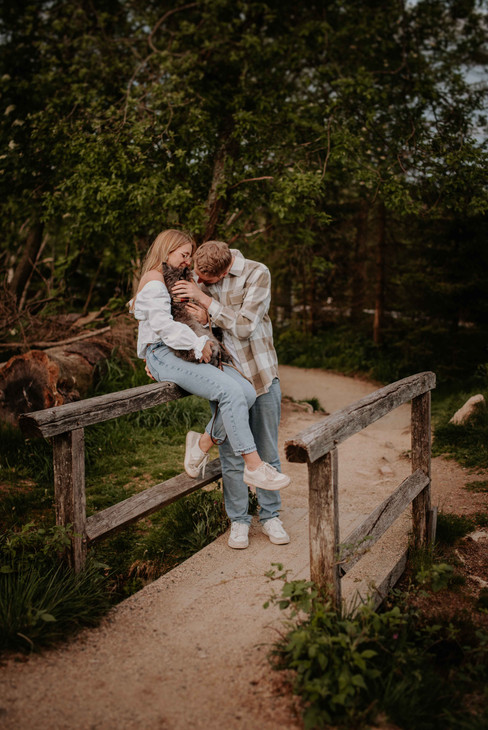 Ein Paar sitzt auf einem Geländer und kuschelt mit seinem Hund
