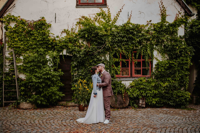 Brautpaar küsst sich vor Gebäude mit Efeu bedeckt, HOCHZEITEN, Hochzeitsfotograf Thüringen.
