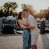 Ein Paar umarmt sich lachend im Sonnenuntergang an einem Hafen