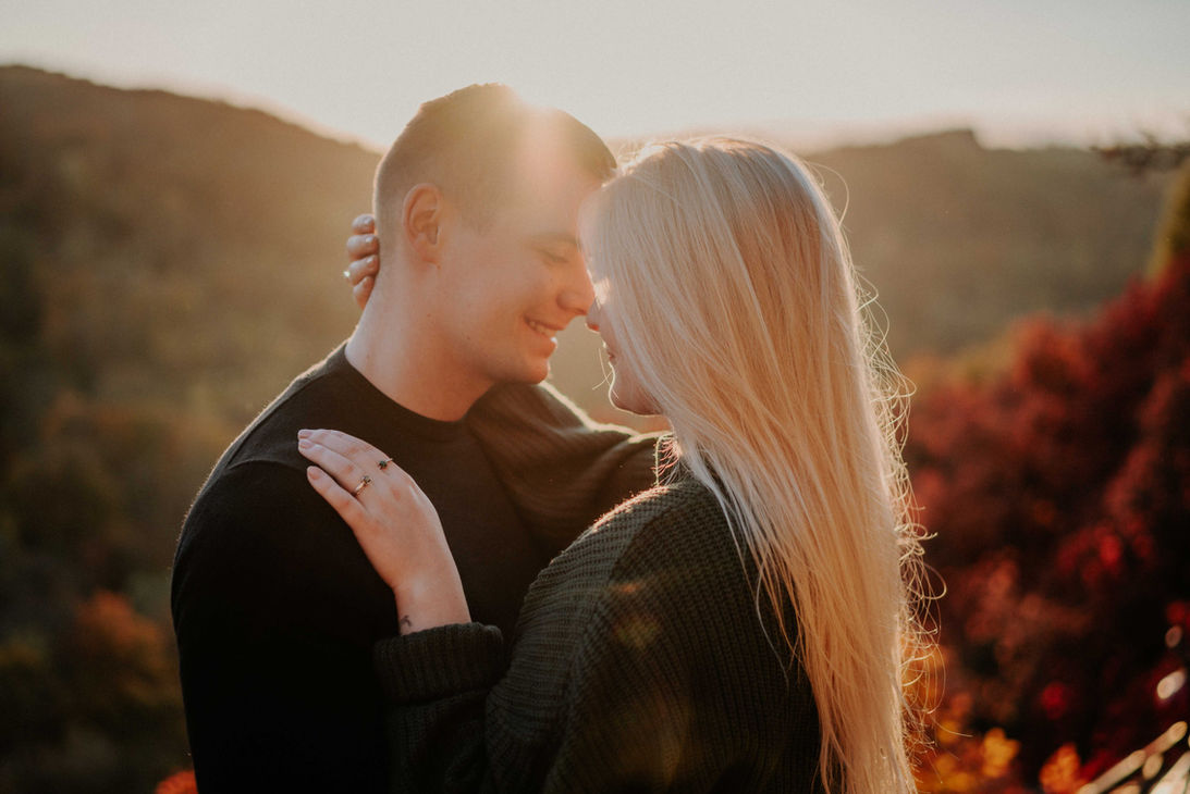 Zärtlicher Moment zwischen einem Paar im herbstlichen Licht der Perückenbüsche in Jena