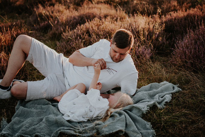 Ein Papa kuschelt mit seiner Tochter auf einer Decke