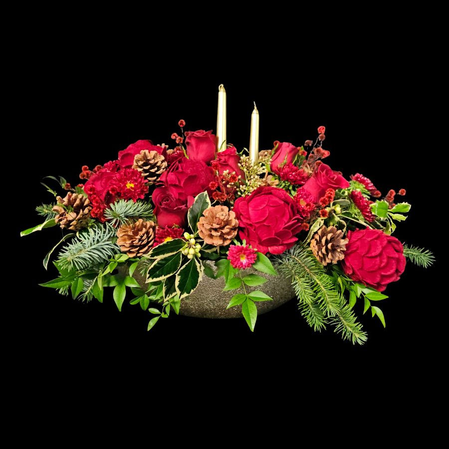 Selection of red flowers, christmas baubles and greenery in a gold vase
