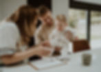 Parents helping baby make handprints on reactive inkless kit paper at a table