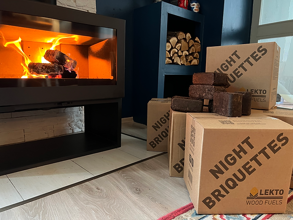 Lekto Night Briquettes Burning in a log burning stove, traditional logs and an opened box of Night Briquettes visible in the background.