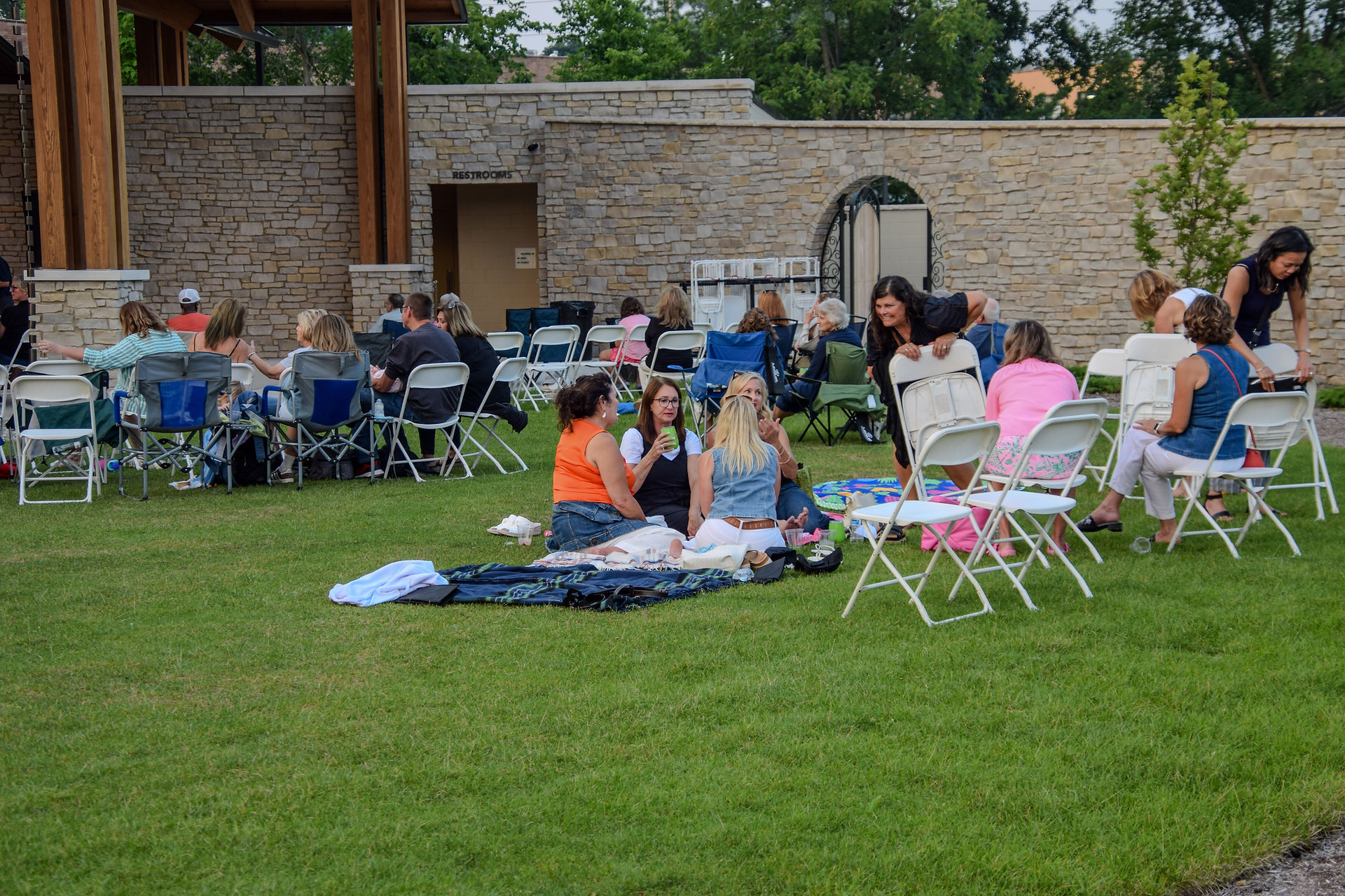 a group of women sitting on towels in the Gardens enjoying the Groovin' in the Gardens concert