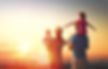 A family of four standing and watching the sunset with their backs to the camera.