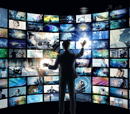 A man standing in front of multiple screens.