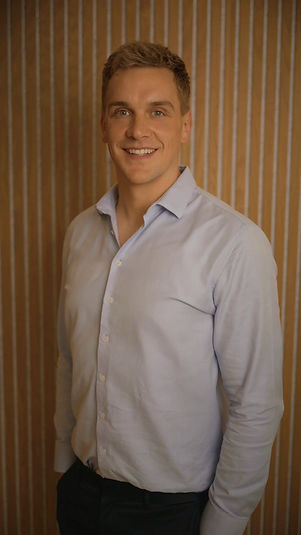 Tom Dixon of Atlas Physiotherapy at SYNC Therapies, photographed against warm timber slats.