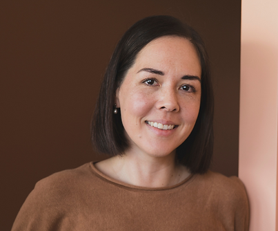 Portrait of Clare Brennan, remedial massage therapist at SYNC Therapies, photographed against warm contrasting walls.