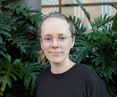 Portrait of Charlotte Curan‑Stevens, remedial massage therapist at SYNC Therapies, photographed with tropical greenery and soft natural light.