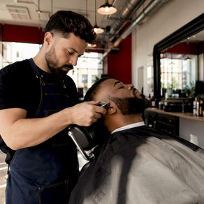 Barber carefully trimming man's beard
