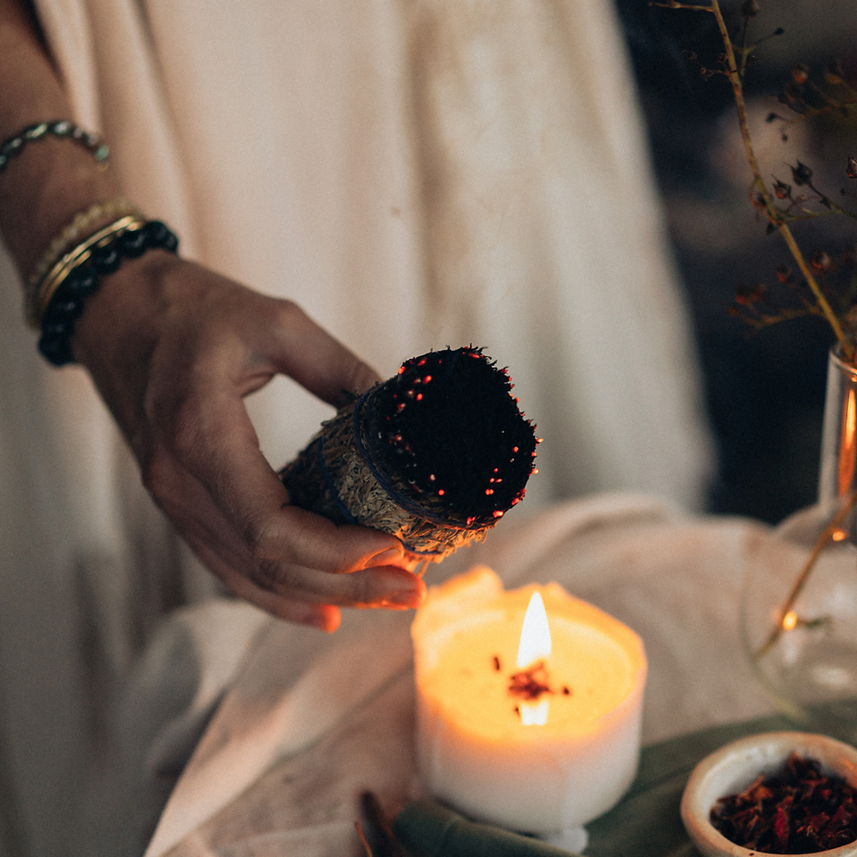 Woman performing smudging ceremony with sage and candle
