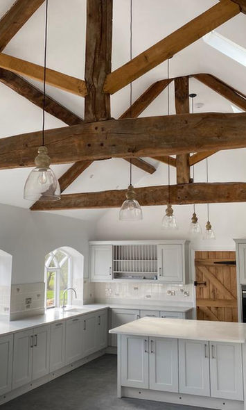 Image of a kitchen refurbishment by  Saville Construction, Worcestershire. White walls and counters with wooden beams overhead.