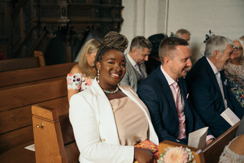 Die Gäste sitzen auf einer Bank in der Kirche.