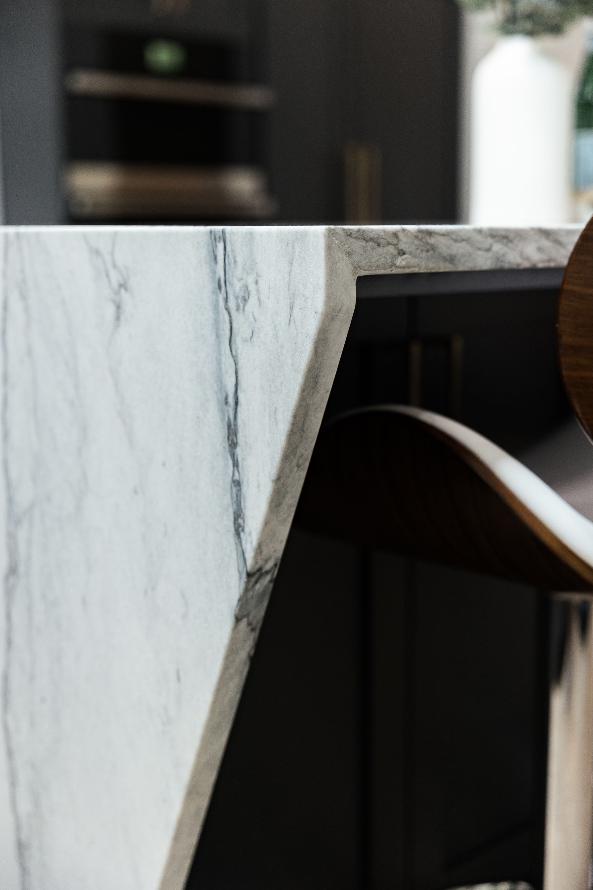 Close up the corner of a waterfall quartzite countertop with dark cabinets below.