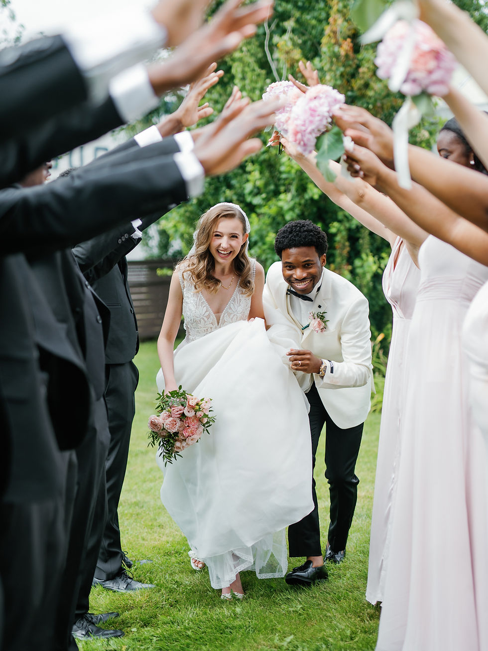 Smiling bride and groom walking through a high-five tunnel